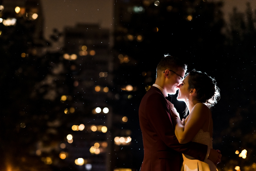A bride and groom hold each other in the rain at night in Philadelphia.